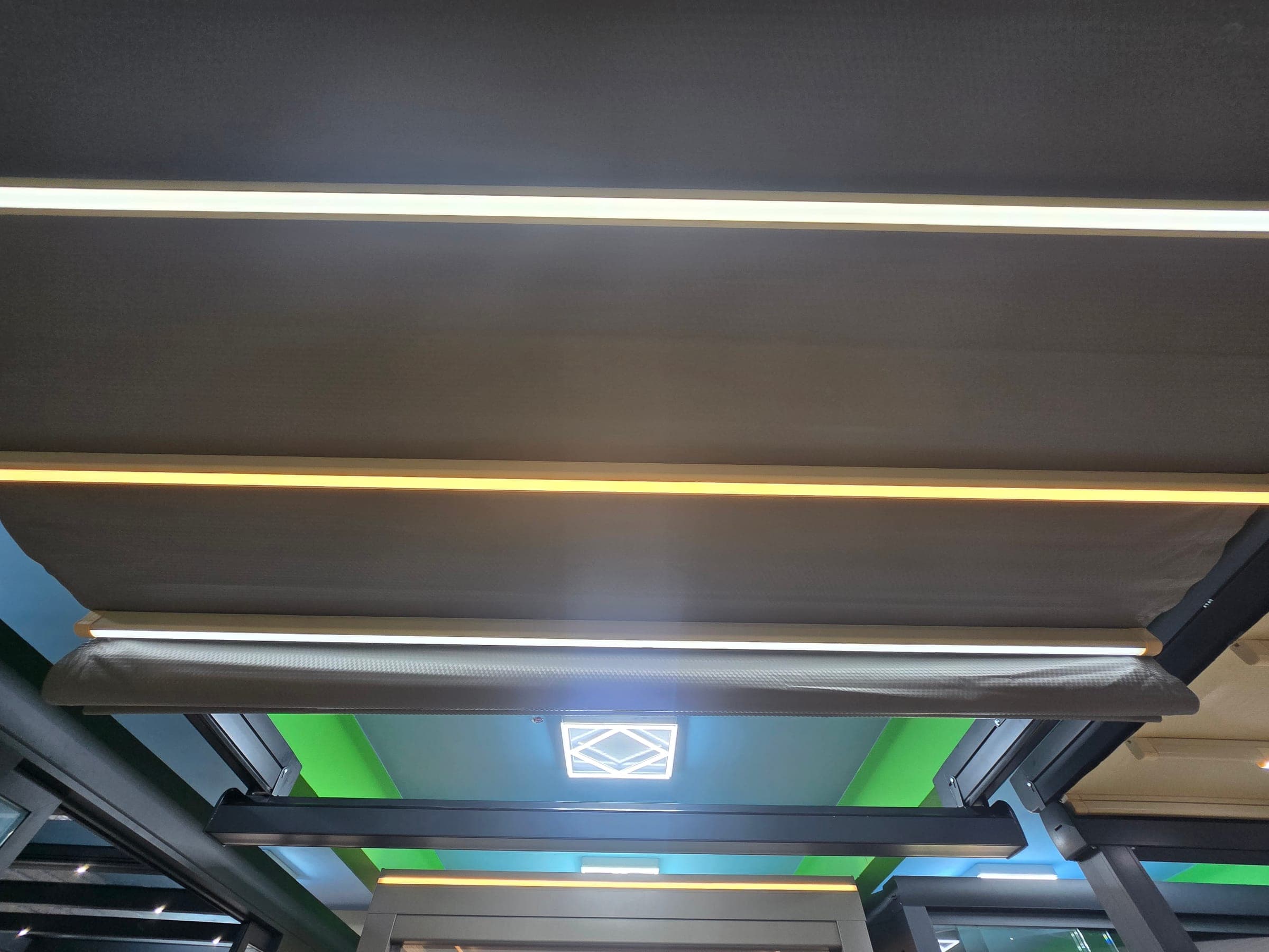 Under-glass automated fabric awning extending under a veranda roof